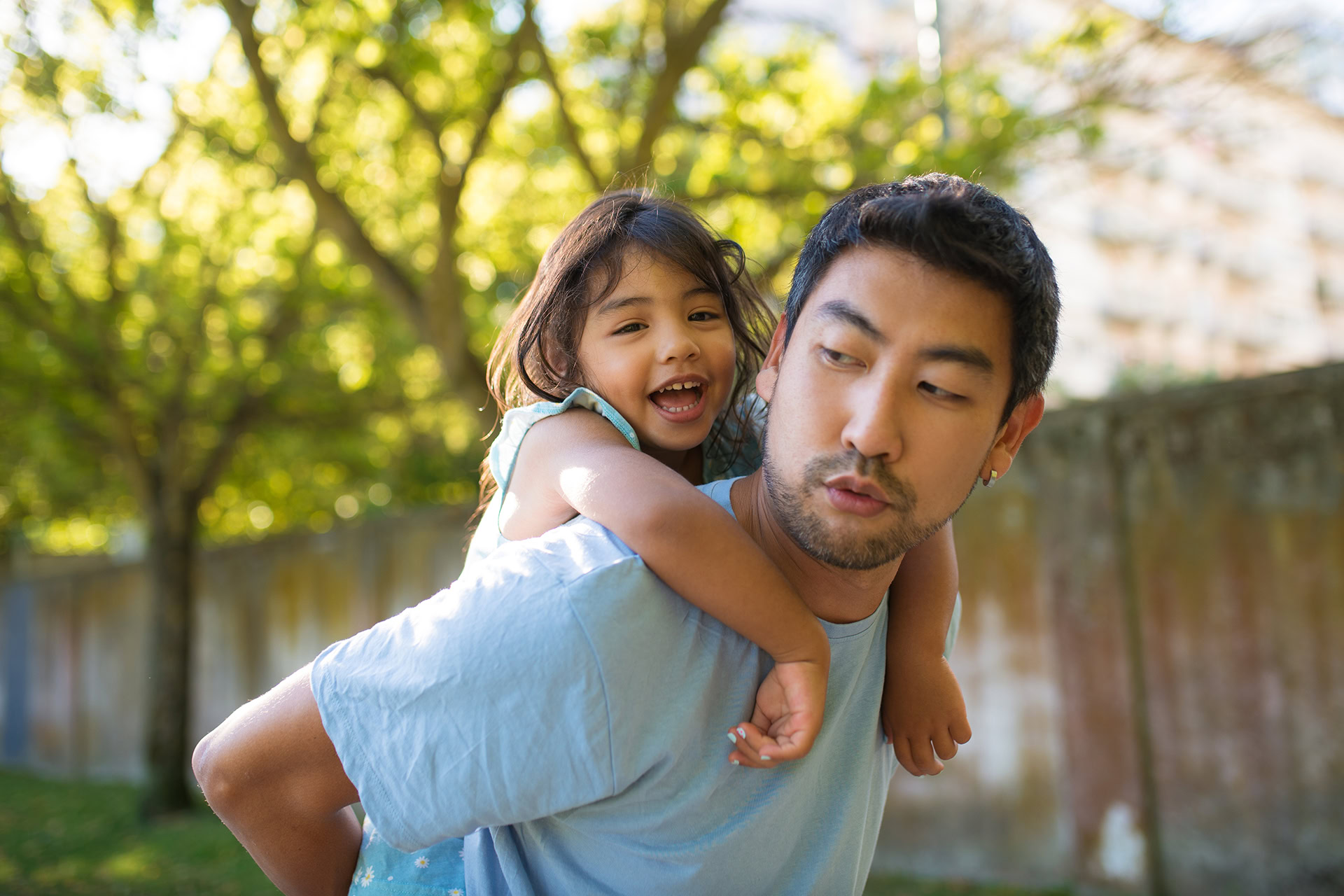 Asian man and little girl having fun in summer park asian man little girl having fun summer park joyful father holding smiling daughter his back walking park spending weekend together childhood leisure summer rest concept
